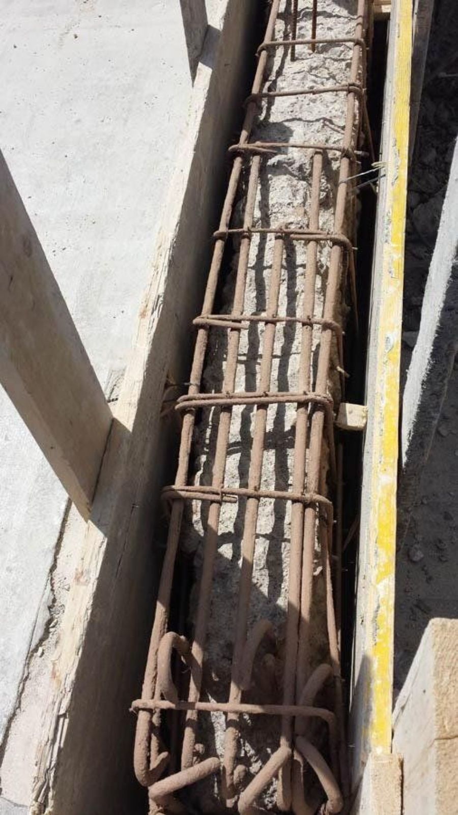 Colonna in cemento armato con barre d'acciaio, parzialmente riempita di calcestruzzo, in un contesto di costruzione.