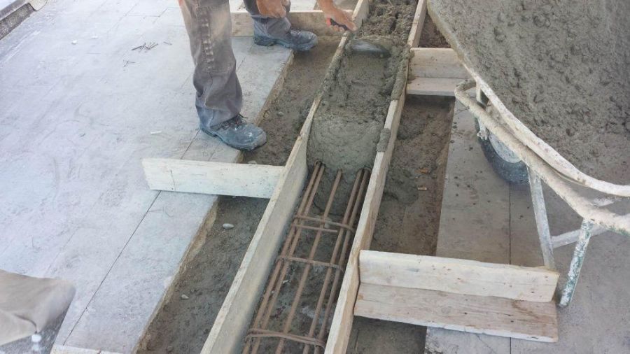 Calcestruzzo versato in una cassaforma di legno con barre d'armatura, cantiere.