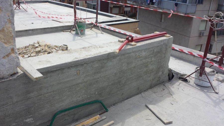 Cantiere con muri di cemento e tetto, barriere di sicurezza e attrezzi.