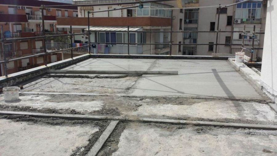 Tetto con superficie in cemento, ringhiere in metallo e condomini sullo sfondo.