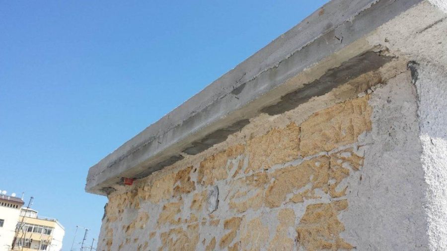 Una sporgenza di cemento in cima a un muro di pietra contro un cielo azzurro.