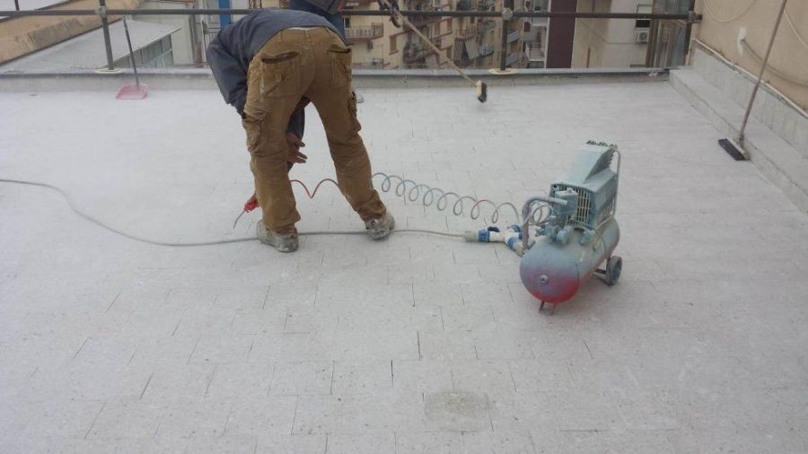 Persona che utilizza un compressore d'aria su un tetto bianco.