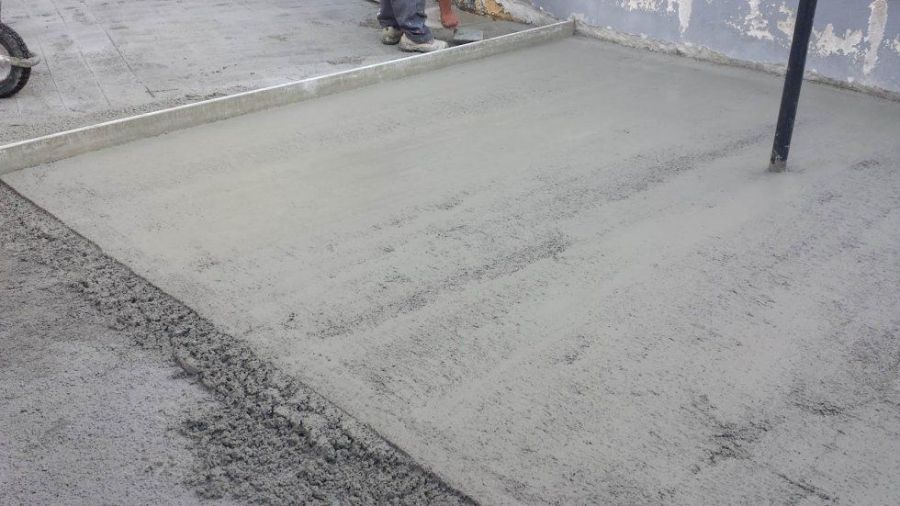 Calcestruzzo appena colato e lisciato con una cazzuola, vicino a un muro.