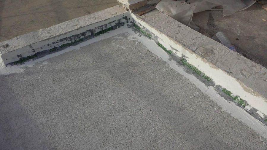 Struttura in cemento con materiale verde visibile in una giunzione angolare, ambiente interno.