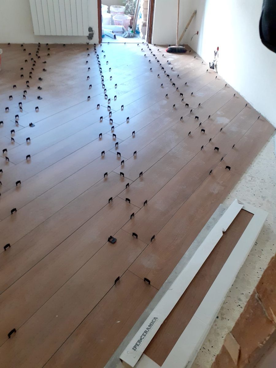 Pavimento con piastrelle e piccoli distanziatori neri, costruzione in corso.