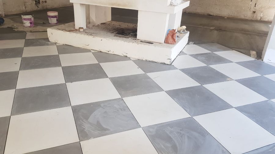 Posa di pavimento in piastrelle a scacchiera con quadrati bianchi e grigi, vicino a un camino bianco.