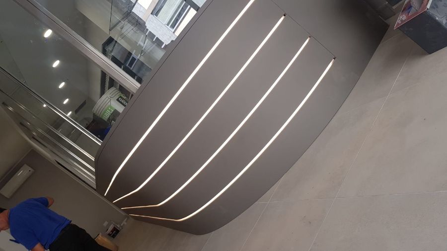 Soffitto curvo con quattro strisce LED orizzontali. Una persona è in piedi sulla sinistra.
