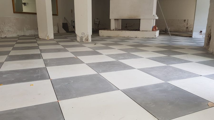 Pavimento in piastrelle a scacchiera in una stanza con pilastri di sostegno bianchi e un camino.