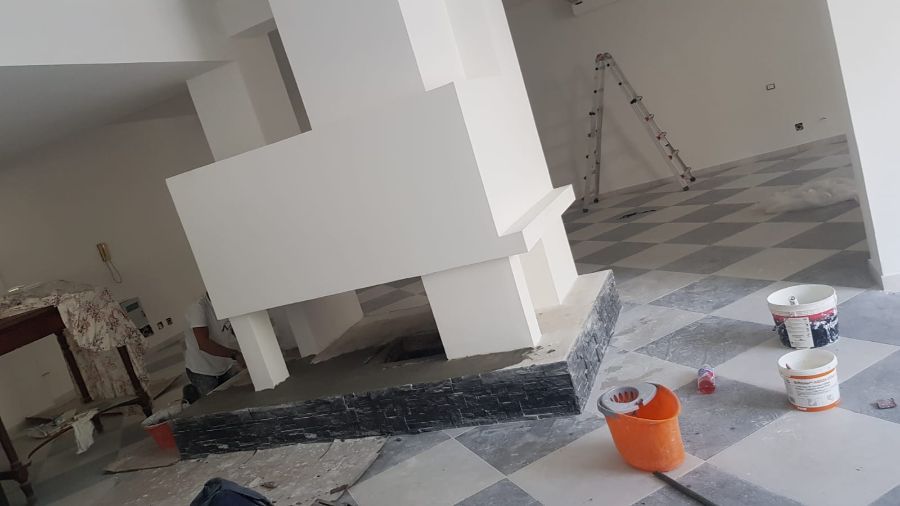 Camino di nuova costruzione dipinto di bianco, con pavimento a scacchi grigi e bianchi e barattoli di vernice.