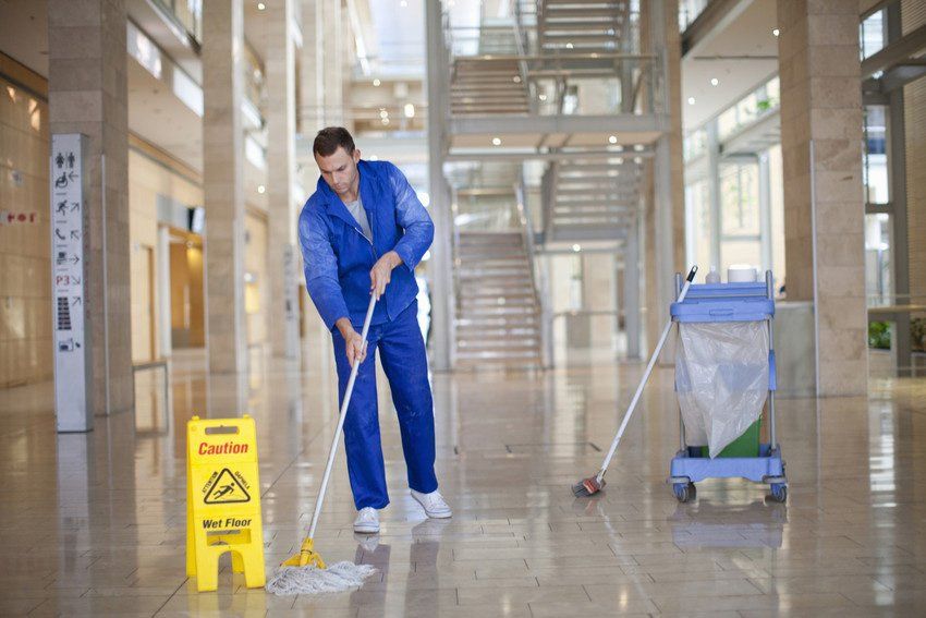Male cleaner mopping in office