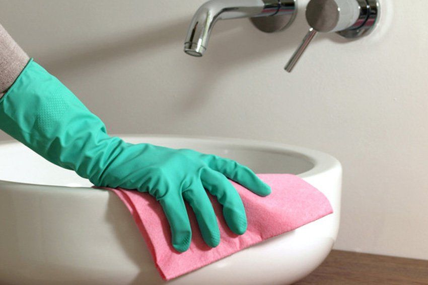 Hand cleaning bathroom sink with glove and rubber