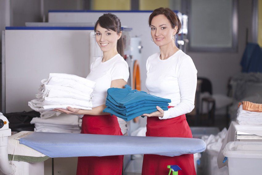 Women with folded clothing front of washing machines