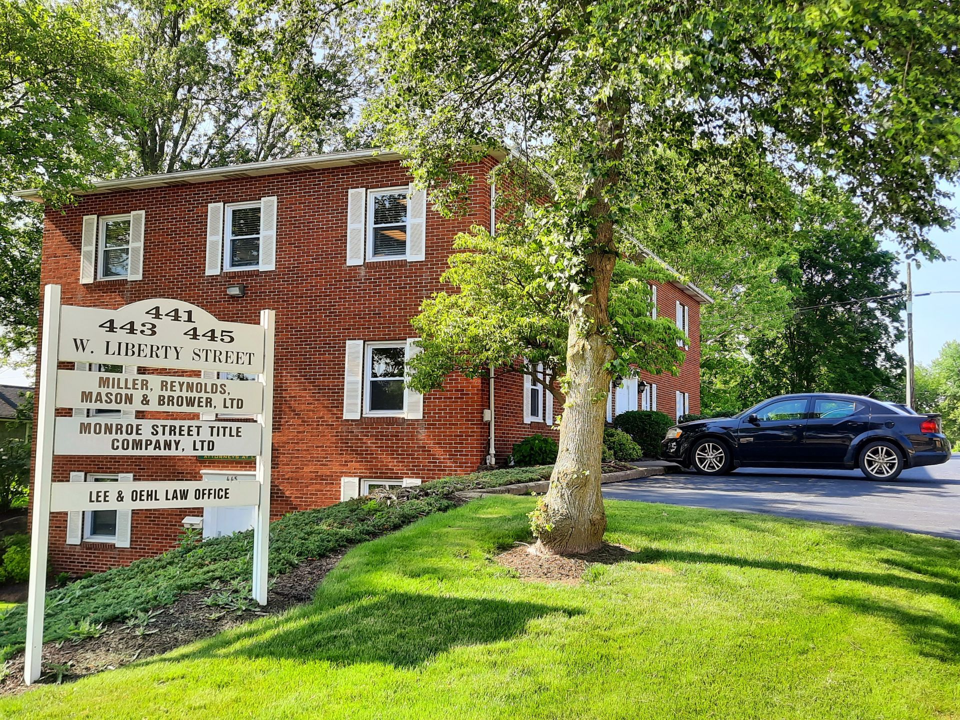 A brick building with a sign in front of it and a car parked in front of it.