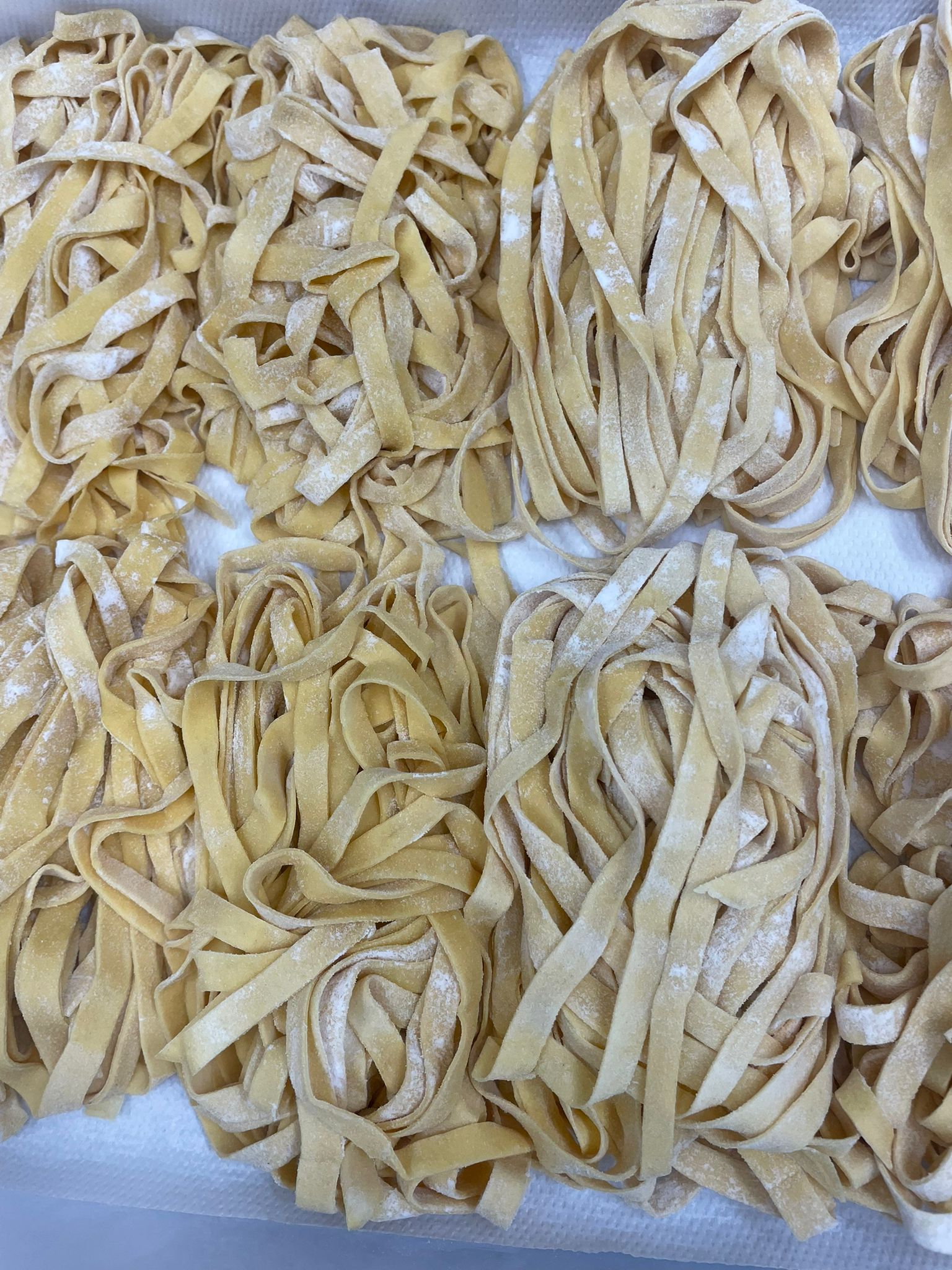 Fagottini di pasta fresca tagliatelle gialle, infarinati, disposti su un vassoio.