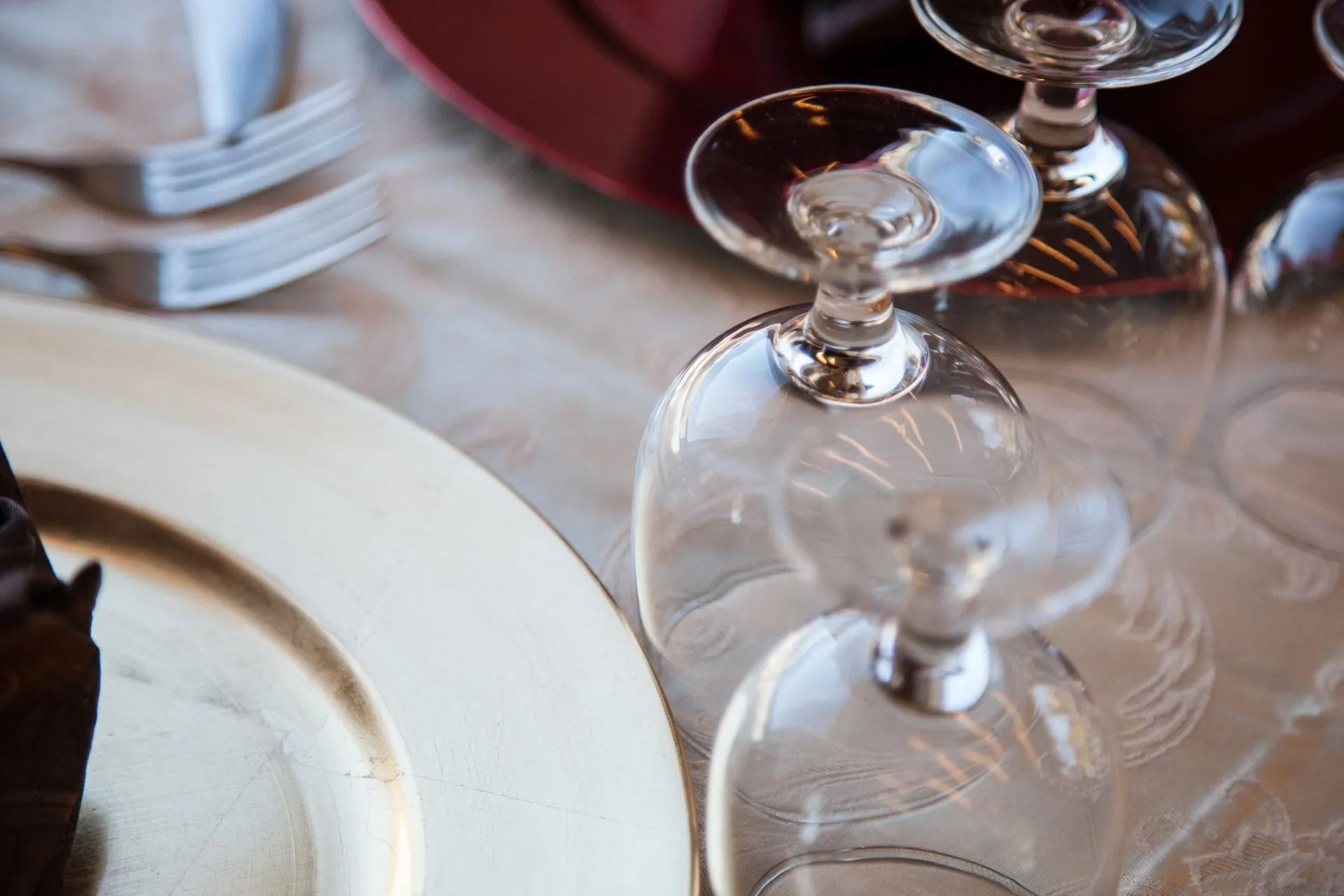Bicchieri da vino rovesciati su una tavola apparecchiata, con un piatto bianco e forchette.