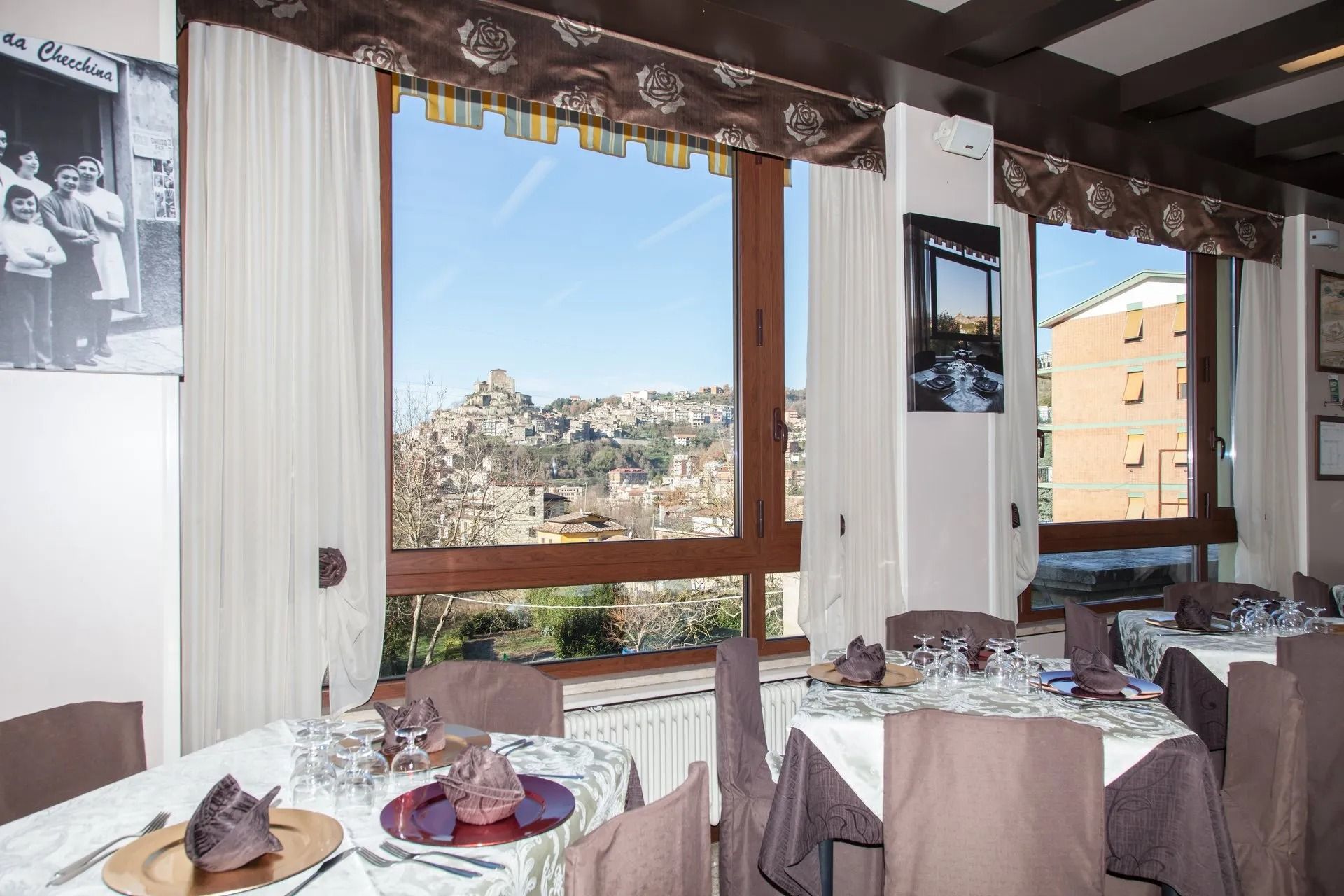 Sala da pranzo del ristorante con tavoli apparecchiati per gli ospiti, con vista sulla città.