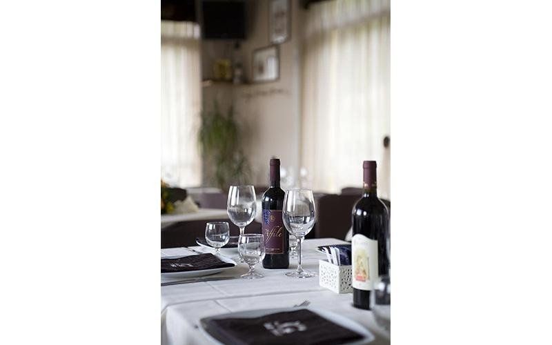 tavoli apparecchiati con bottiglie di vino rosso