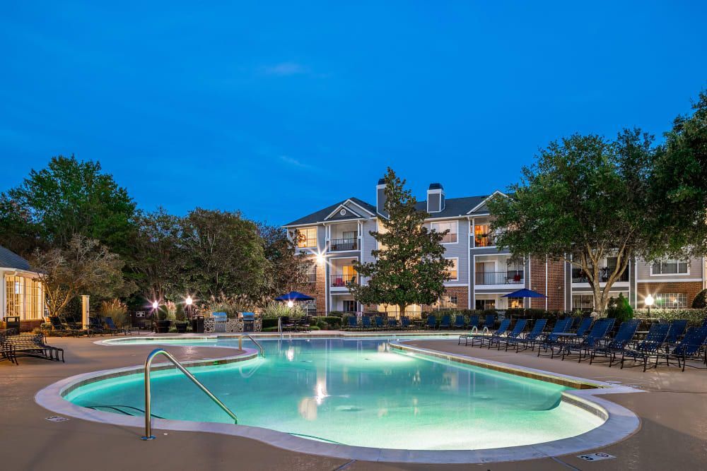 a large swimming pool is lit up at night in front of a building at Marquis Carmel Valley in Charlotte, NC.