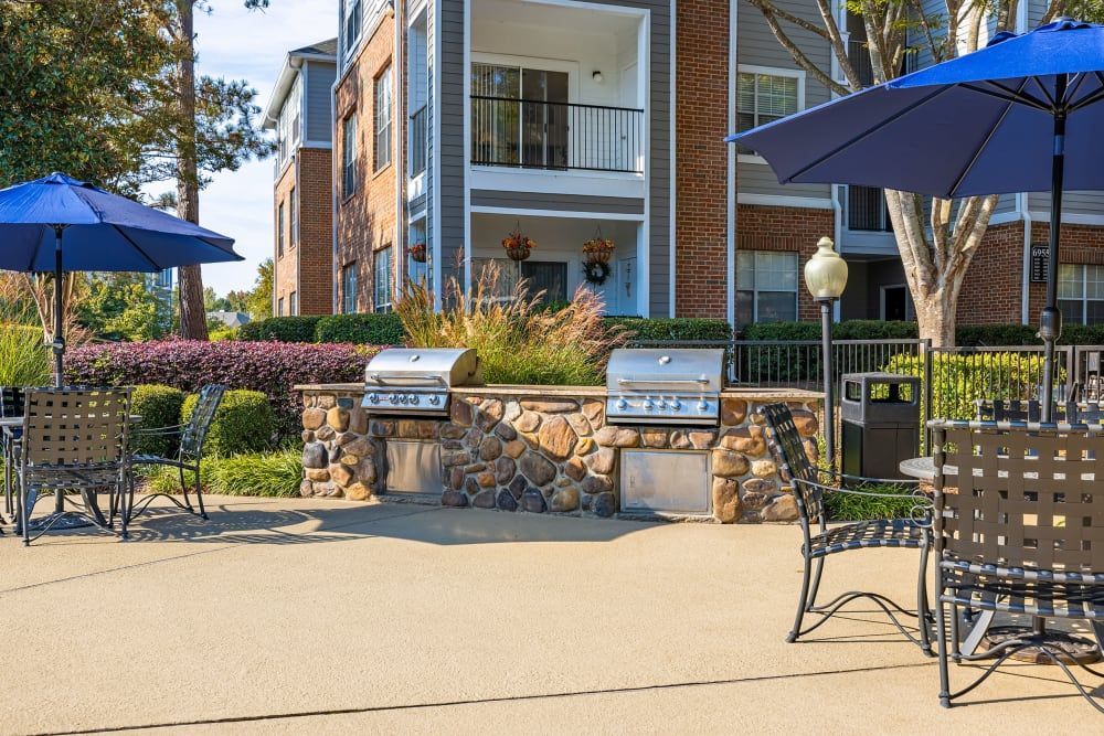 a patio area with tables and chairs and umbrellas in front of a building at Marquis Carmel Valley in Charlotte, NC.