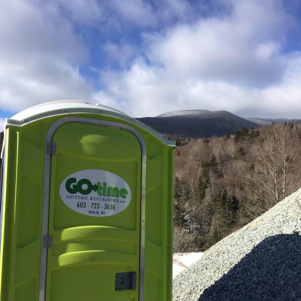 Lime green portable toilet with mountain backdrop; 