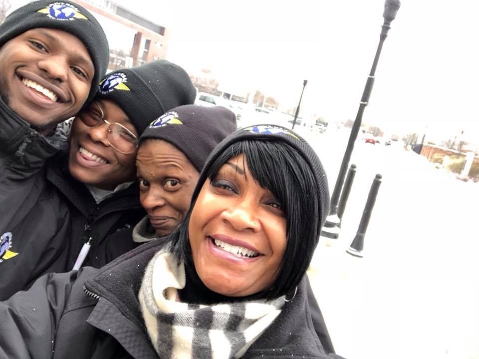 Group selfie in winter, smiling; all wearing black hats and jackets; snow on ground.