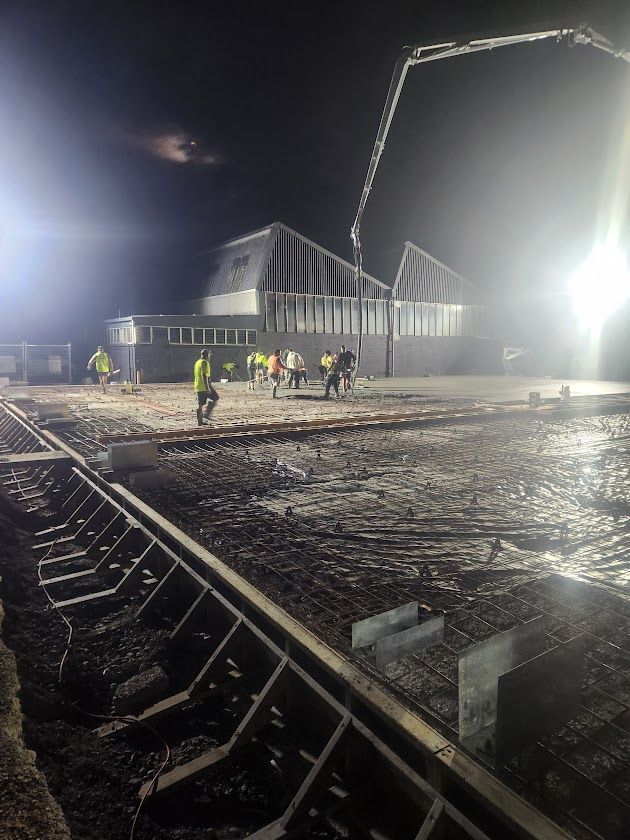A group of people are working on a construction site at night.