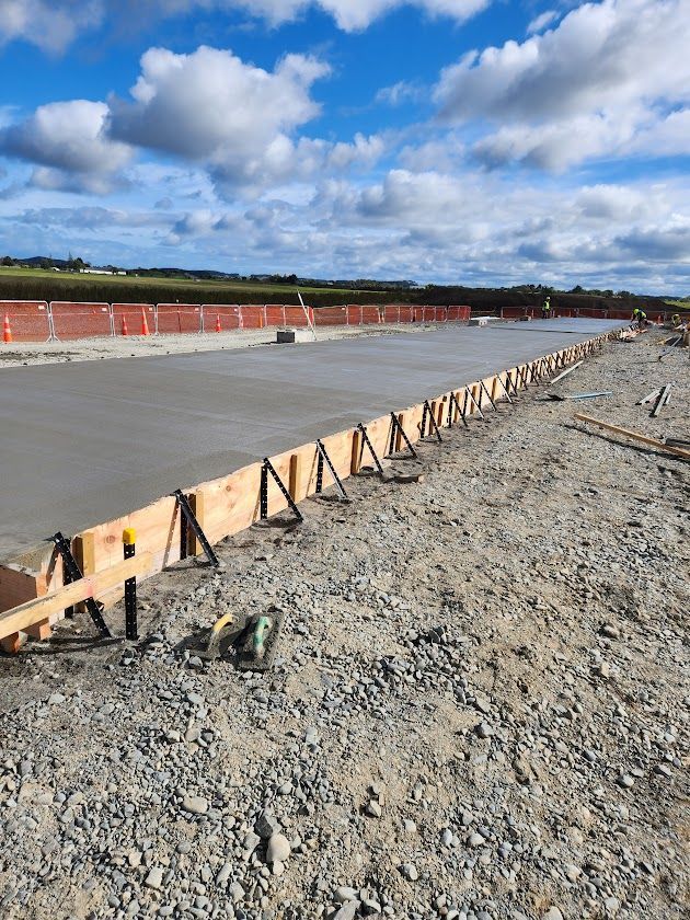 A concrete road is being built on a dirt field.