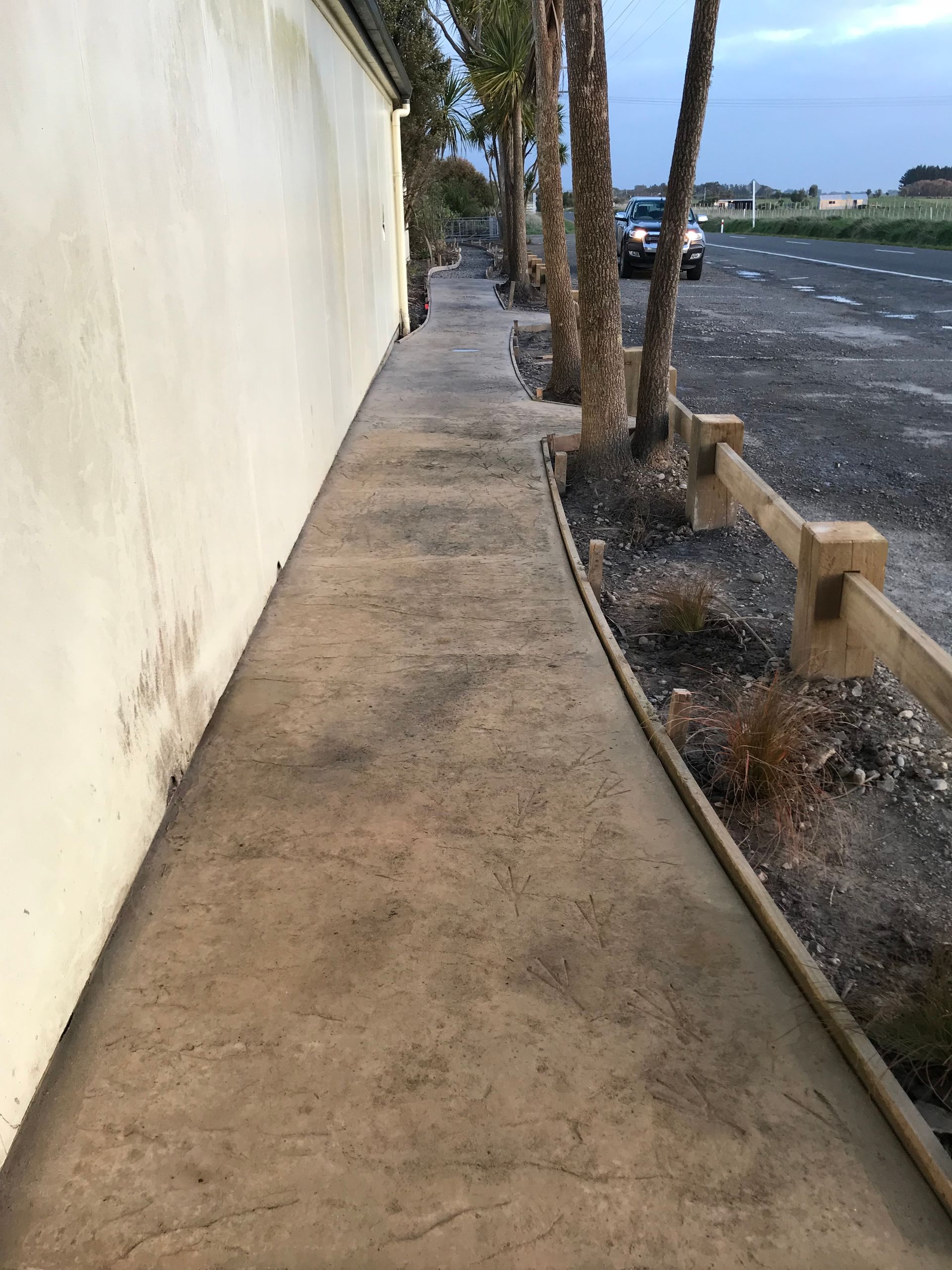 A concrete sidewalk with a wooden fence on the side of it.