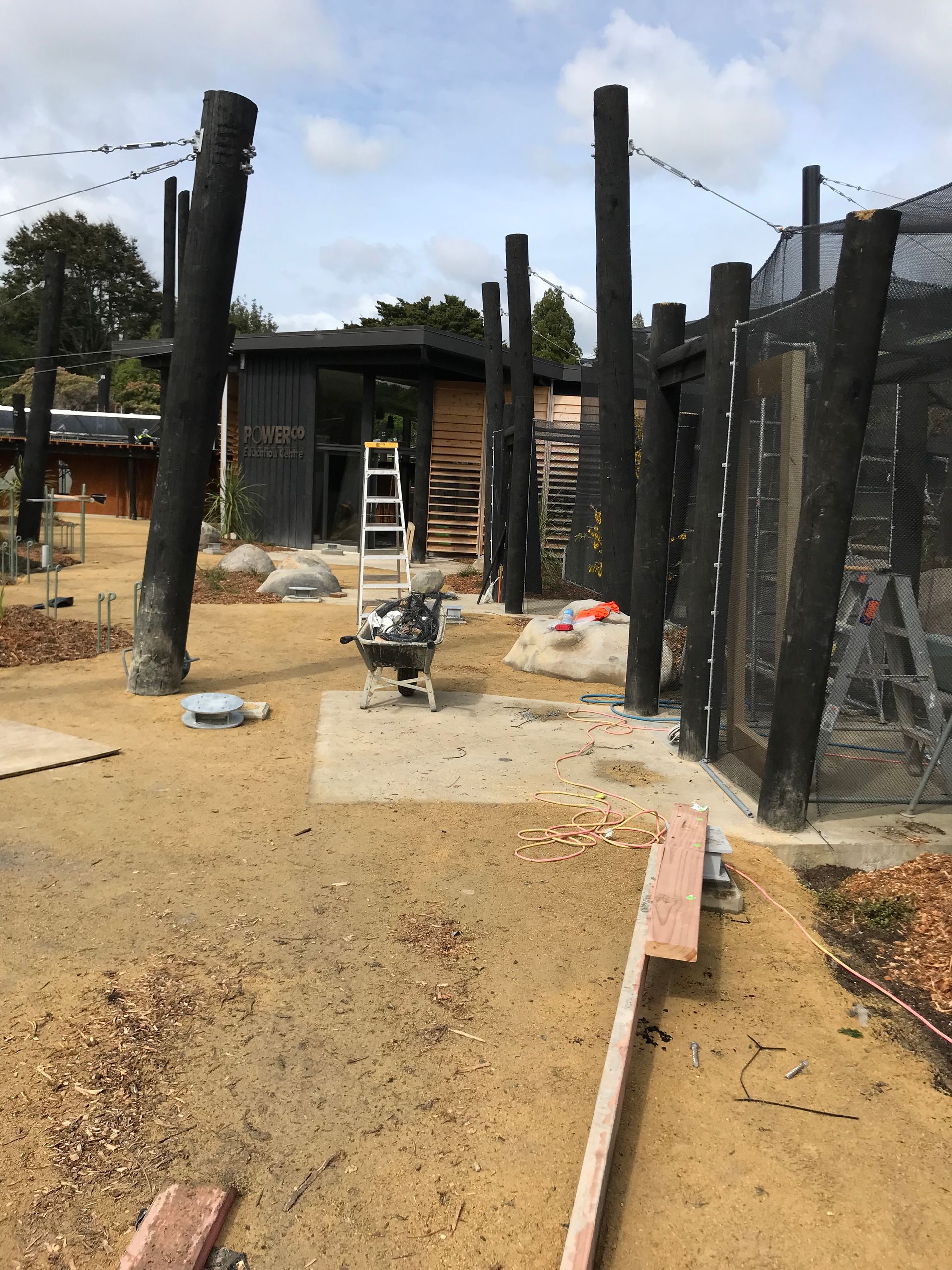 A ladder is sitting in the dirt in front of a building under construction.