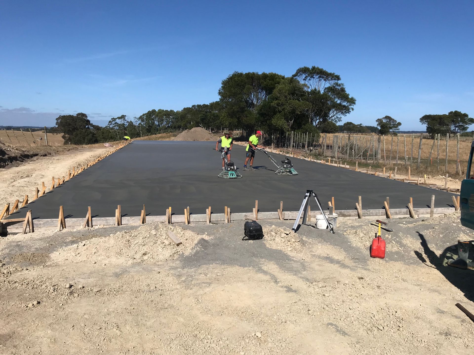 A group of construction workers are working on a concrete road.