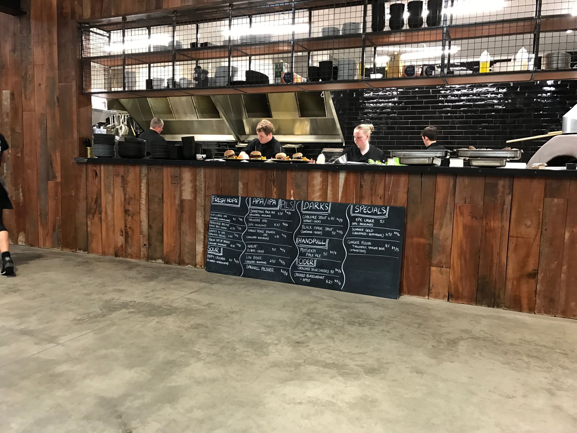 A person is standing in front of a wooden counter in a restaurant.