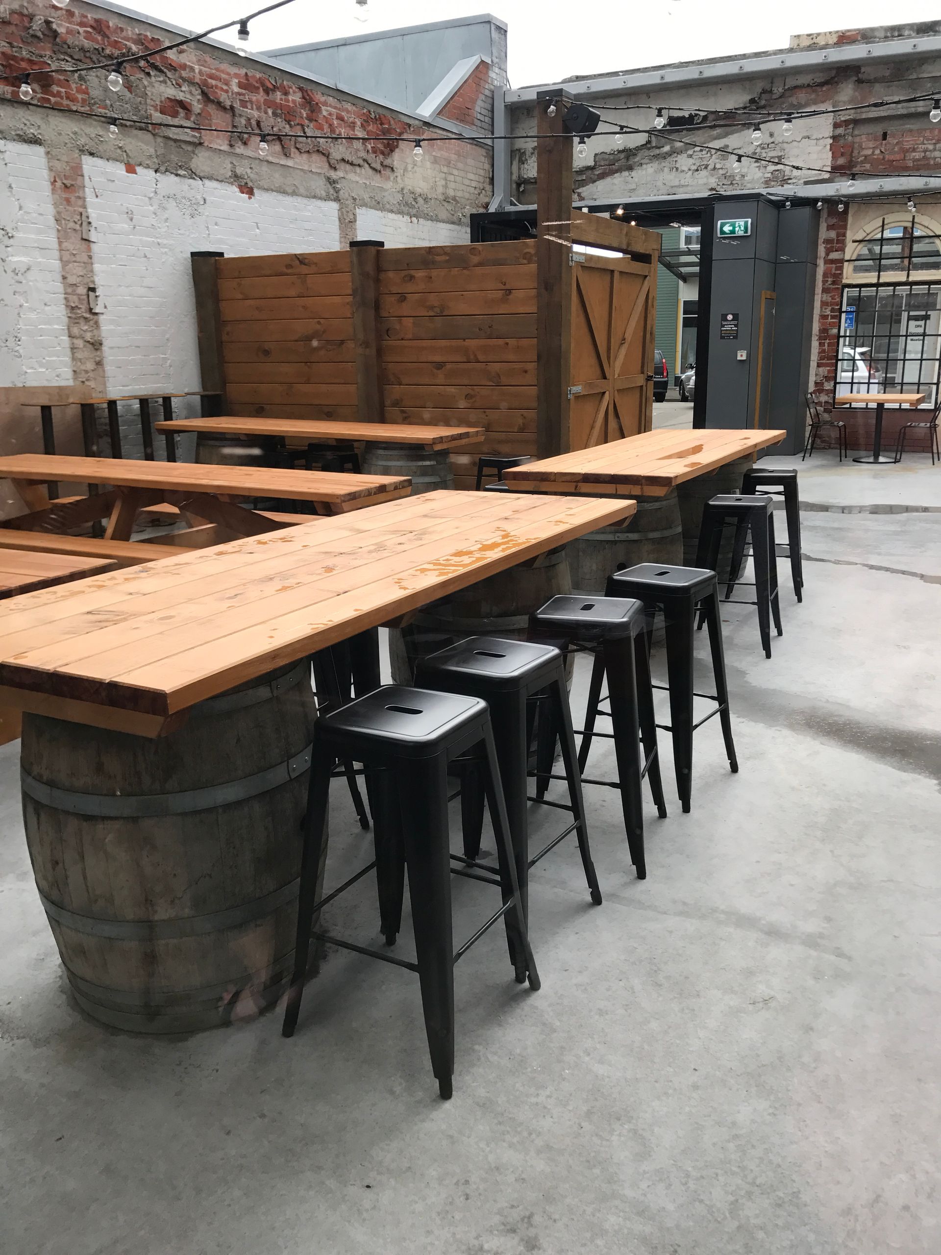 A row of wooden tables and stools outside of a building