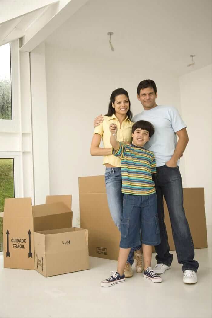 Una familia está parada en una habitación con cajas de cartón.