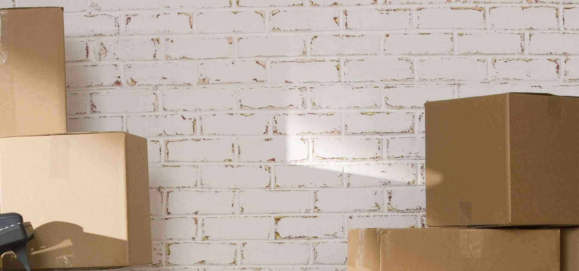Una pila de cajas de cartón contra una pared de ladrillo blanco.