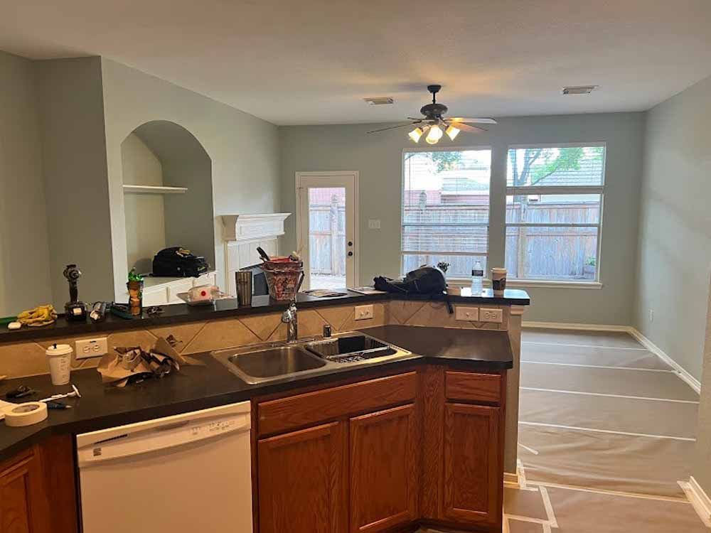Kitchen with wood cabinets, black countertop, stainless steel sink, and light green walls.