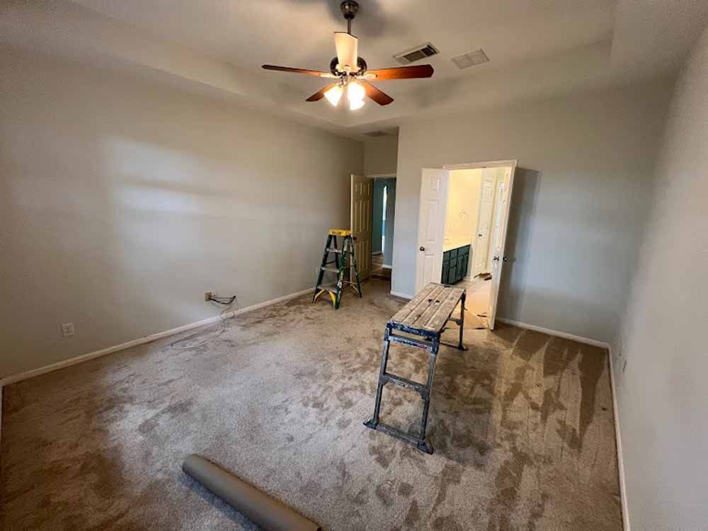 Room under renovation with paint, a ladder, and dirty carpet.