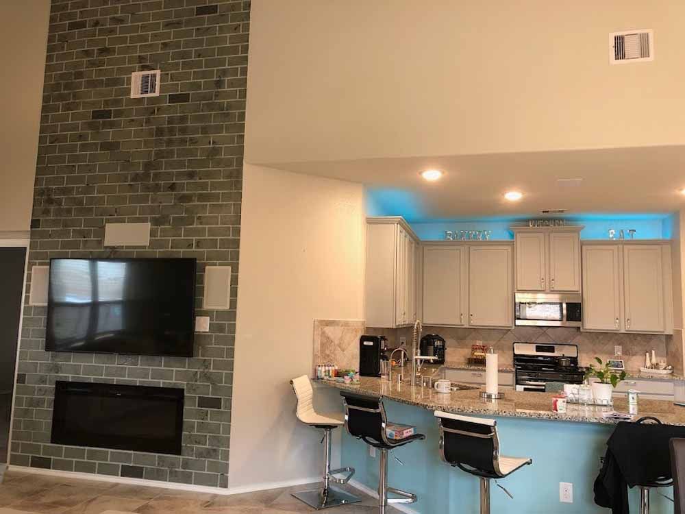 Kitchen with brick fireplace, light blue island, and grey cabinets.