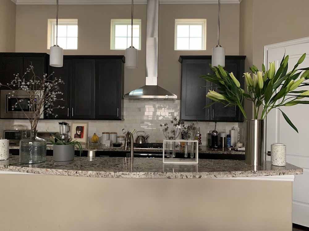 Kitchen with dark cabinets, granite countertop, stainless steel hood, and pendant lights.