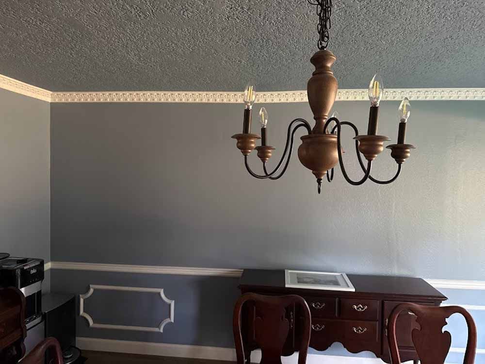 Gray dining room with a chandelier, a dark wooden sideboard, and decorative wall molding.