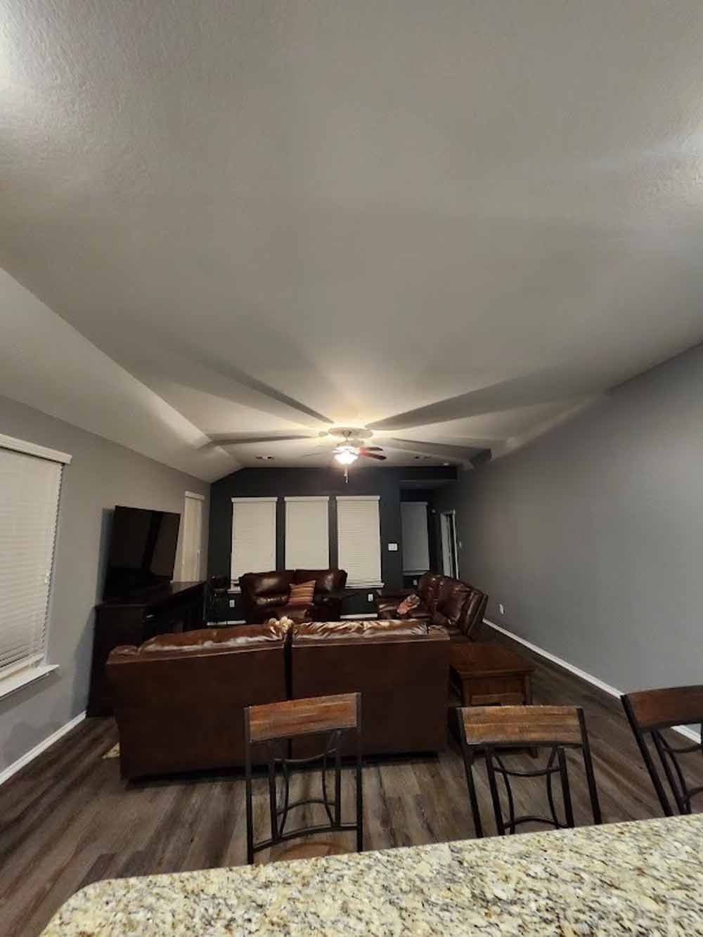 Living room with brown leather furniture, wood floors, and gray walls.