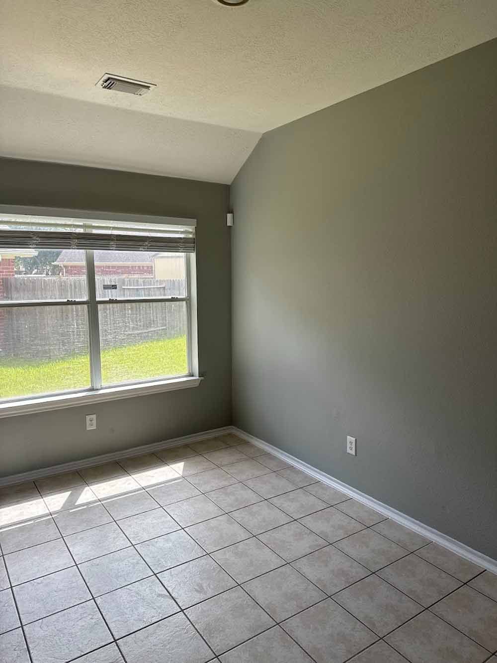 Empty room with gray walls, window, and tiled floor.