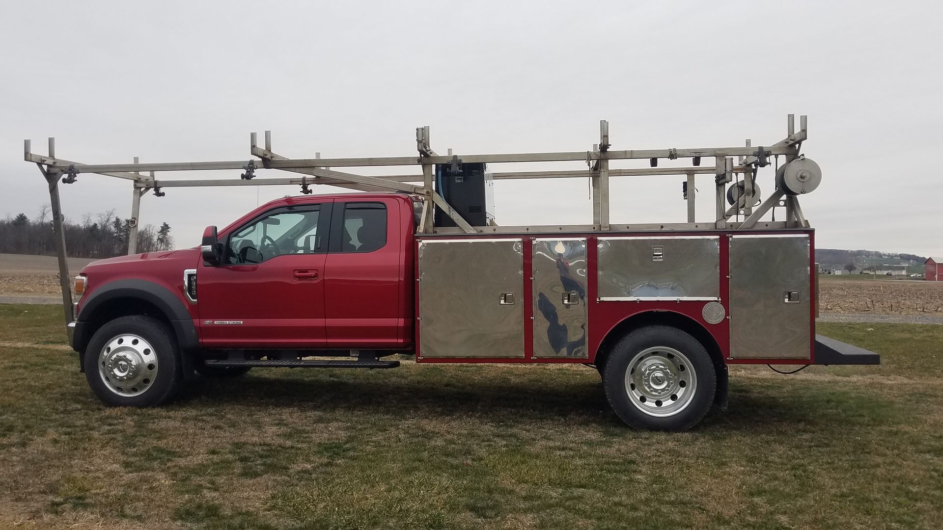 A red truck is parked in a grassy field.