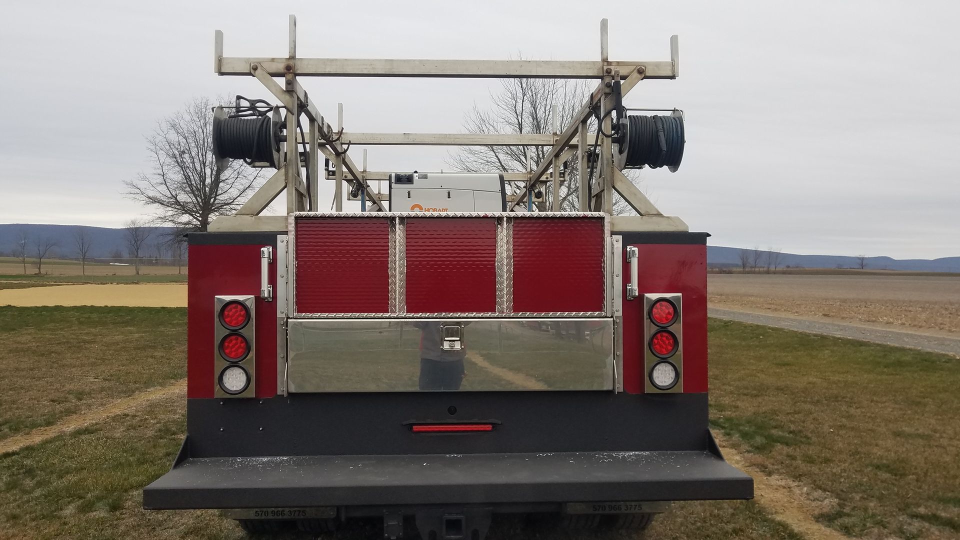 A red and black truck is parked in a field
