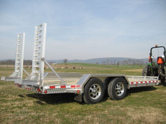 A trailer is parked in a grassy field next to a tractor.