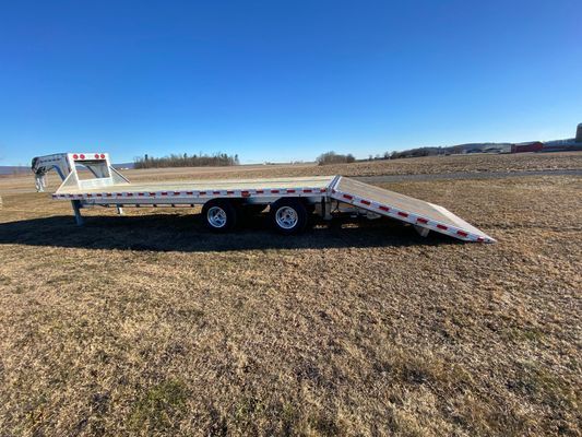 A flatbed trailer is parked in the middle of a field.