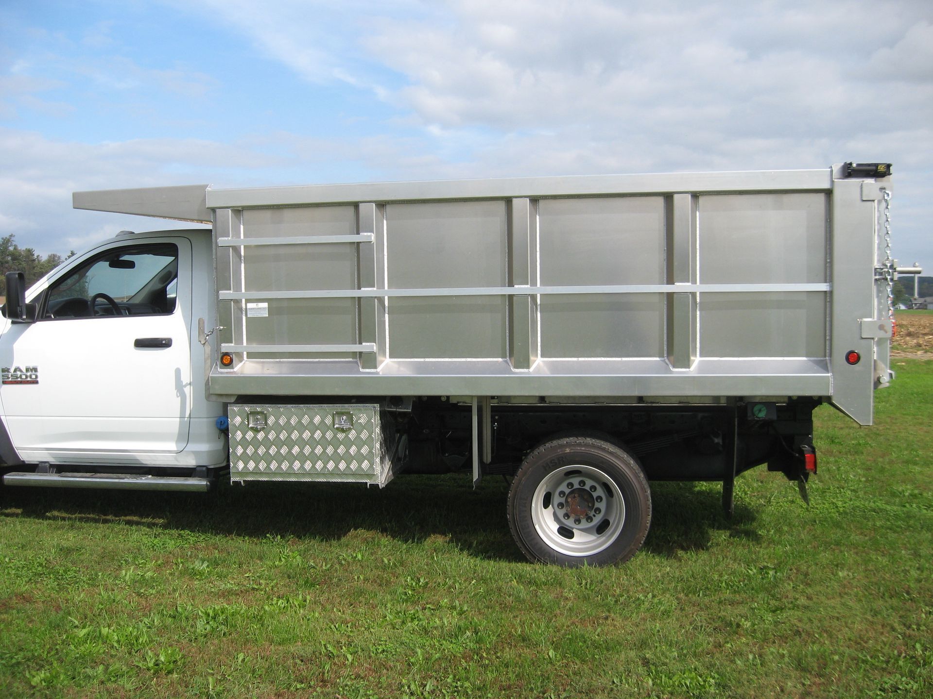 A white dump truck is parked in a grassy field
