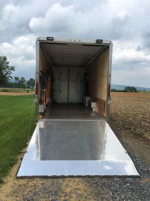 A trailer is sitting on top of a gravel road in a field.