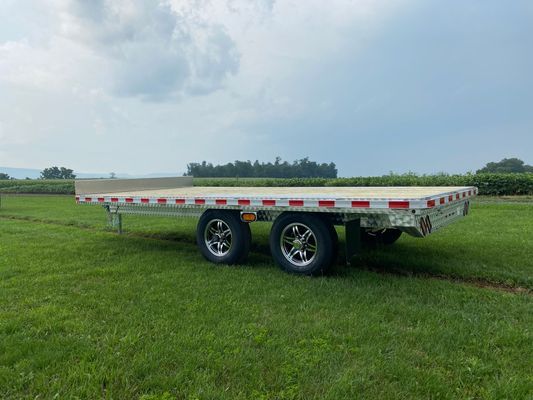 A flatbed trailer is parked in a grassy field.