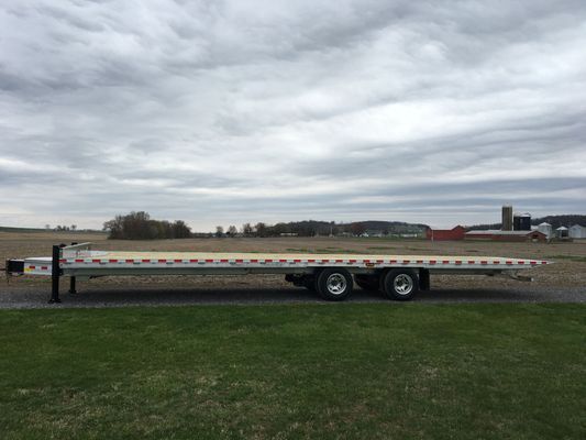 A flatbed trailer is parked in a grassy field.