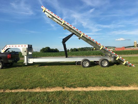 A truck is towing a flatbed trailer with a ladder attached to it.
